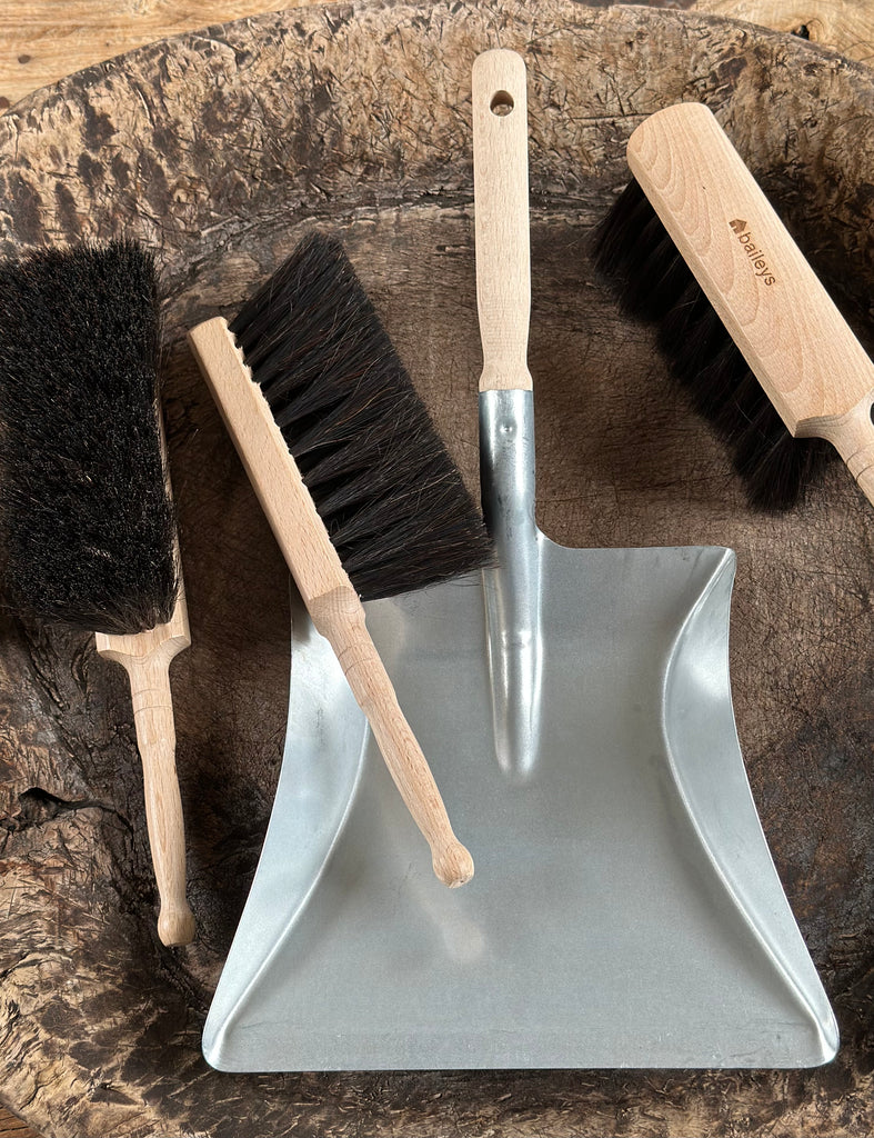 Set of cleaning tools including a dustpan and brushes on a wooden surface