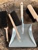 Set of cleaning tools including a dustpan and brushes on a wooden surface