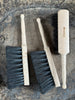 Three brushes with wooden handles on a stone surface