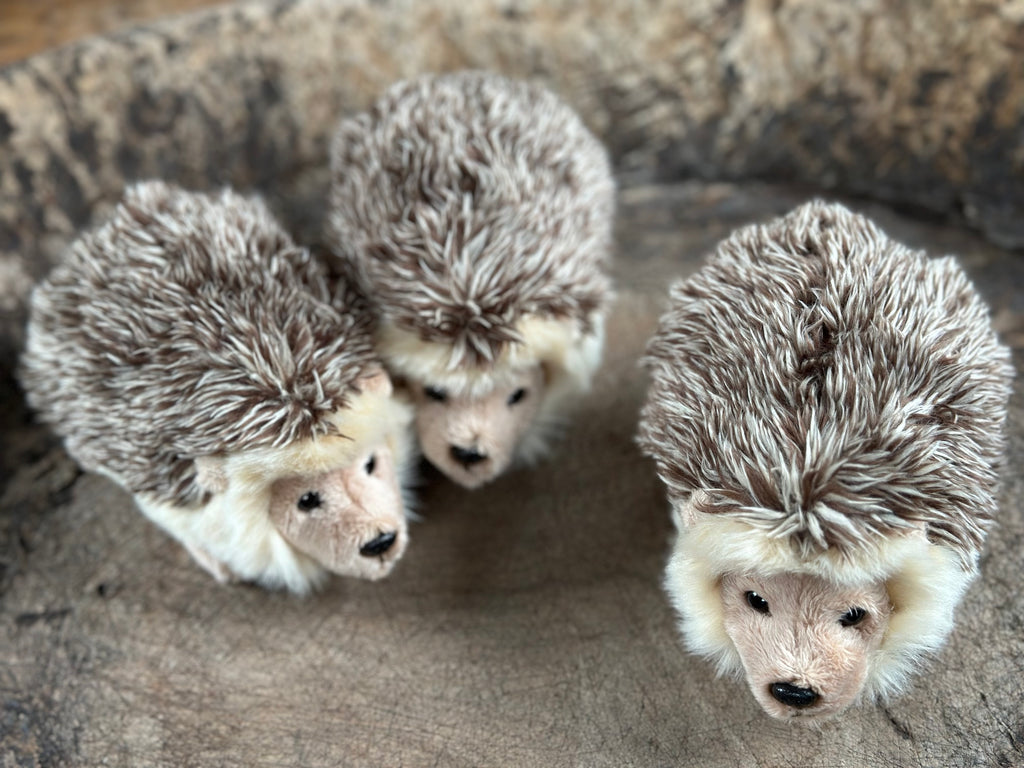Three hedgehog toys arranged in a circle on a textured surface.