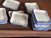 Stacks of white square plates with blue rims on a brown surface