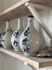 White ceramic bottles with blue text on a wooden shelf