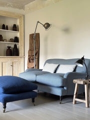 Living room with a blue sofa, ottoman, and wooden side table.