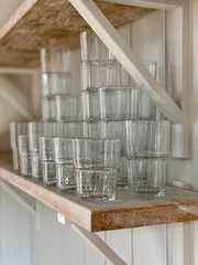 clear, ridged stacking glasses in two sizes on a wooden shelf.