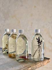 baileys scented bath oils. each one is in a clear glass bottle with dried botanicals and a white lid.