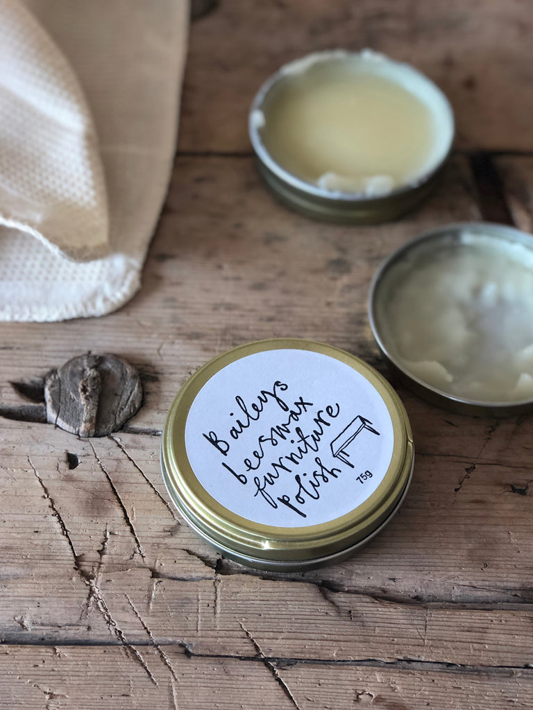 Metal tins of beeswax furniture polish with white printed label.