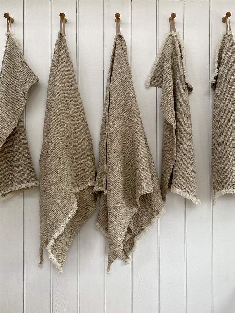Waffle textured towels, natural colour with light fringe. Hanging loop in natural colour. Displayed on hooks.