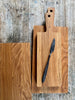 Honey coloured, natural oak chopping boards. Long, rectangular shape with handle. Hole in handle for hanging.