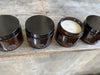 baileys very large, lidded candle jars filled with soy wax candles. brown glass, clear label, black lid.