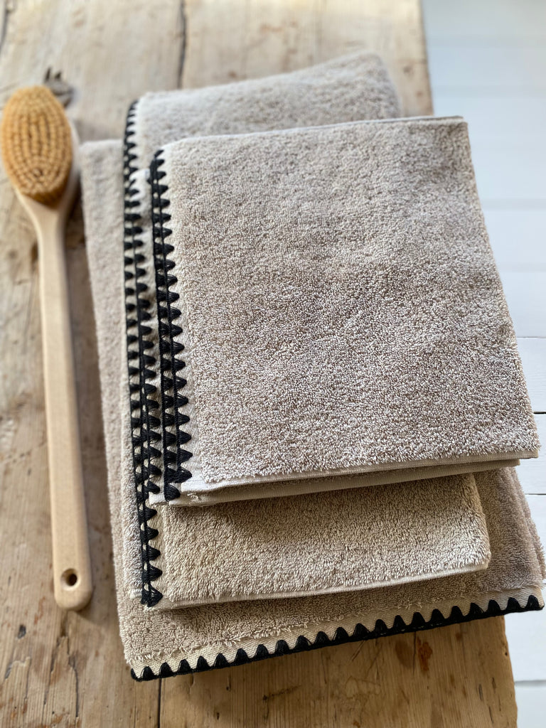 soft fluffy towels in a natural colour with a black blanket stitch effect edging.